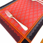 Decorative orange and black patterned tablecloth with a fork on a white background