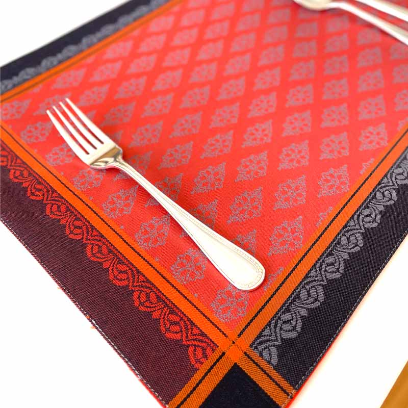 Decorative orange and black patterned tablecloth with a fork on a white background