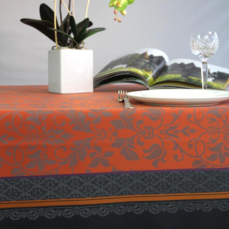 Decorative Orange and black jacquard tablecloth on a set dining table.