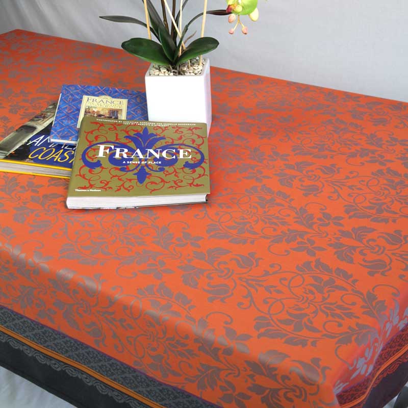 Orange and black jacquard tablecloth on a table, featuring books and a plant.