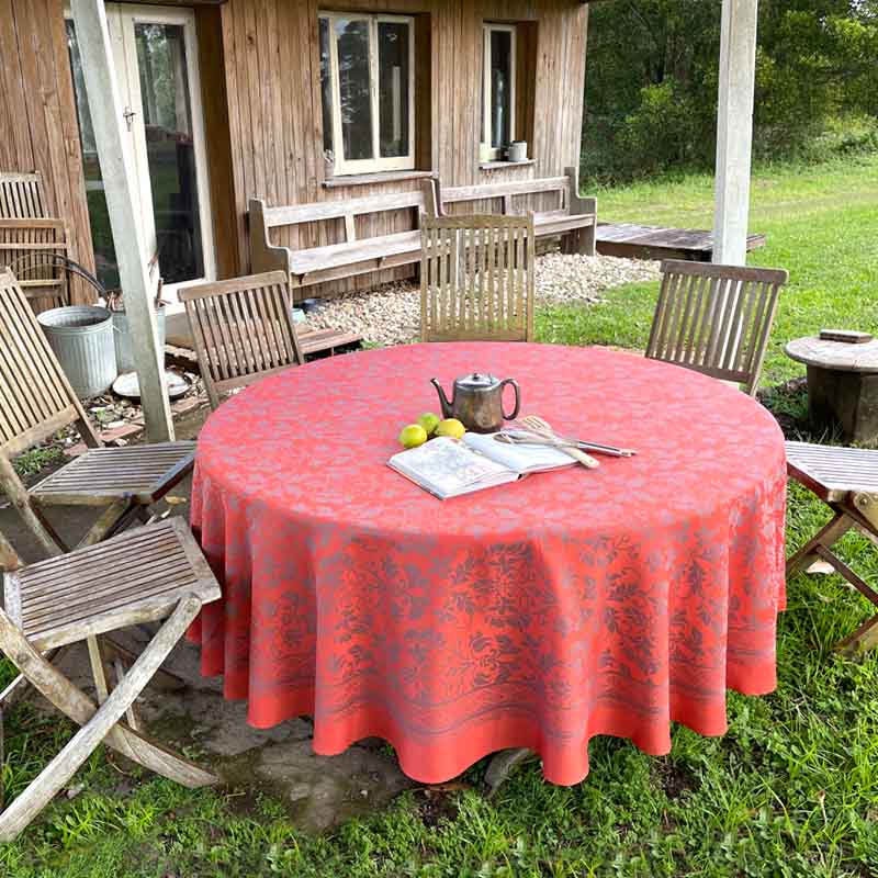 Round table with a orange tablecloth outdoors near a wooden cabin