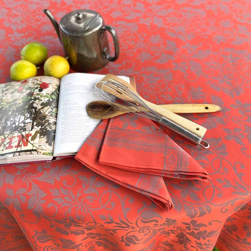 Orange patterned tablecloth with a book, teapot, and wooden utensils on top