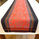 Decorative table runner with red and black pattern on a white surface
