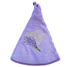 A lavender purple hand towel with a textured honeycomb pattern, featuring an embroidered lavender bouquet and a gold bastide on the front, complete with a hanging loop at the top.