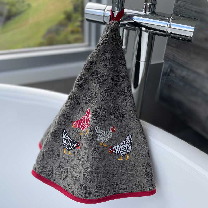 Gray towel with chicken designs hanging on a faucet