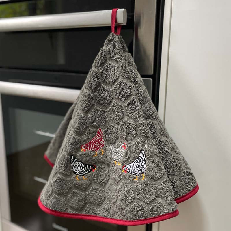 Gray textured hand towel with chicken designs hanging on a kitchen towel rack.