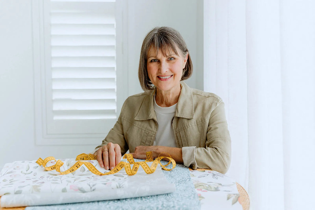 Sue McGary sitting with fabrics and a tape measure