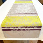 Decorative table runner with yellow and purple patterns on a white surface