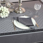 Elegant table setting with silverware, plates, and a floral arrangement on a patterned tablecloth.