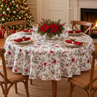 Laponia round Christmas tablecloth with red flowers and green foliage, set with red napkins and white plates